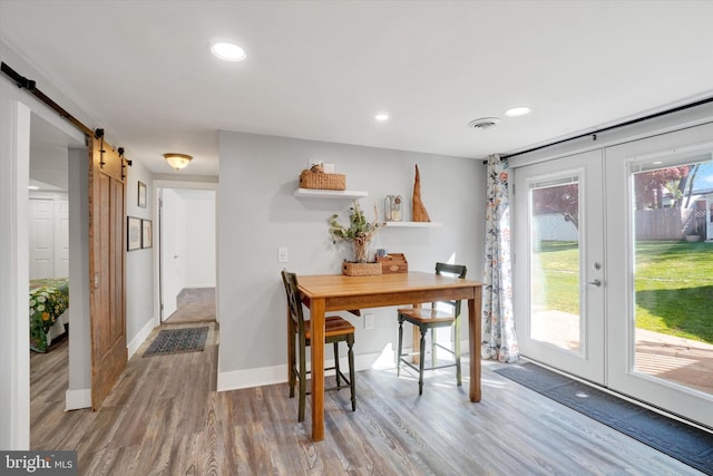 dining area with wood finished floors, baseboards, recessed lighting, a barn door, and french doors