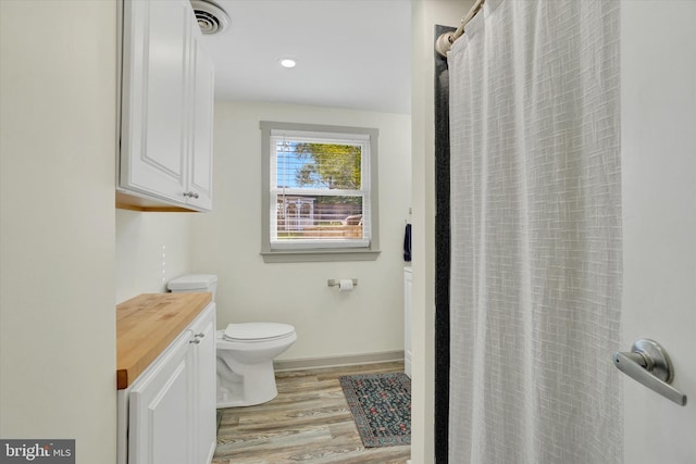 full bath featuring a shower with curtain, visible vents, wood finished floors, baseboards, and toilet