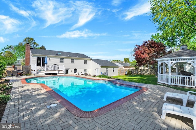 outdoor pool featuring a lawn, a wooden deck, fence, a patio, and a gazebo