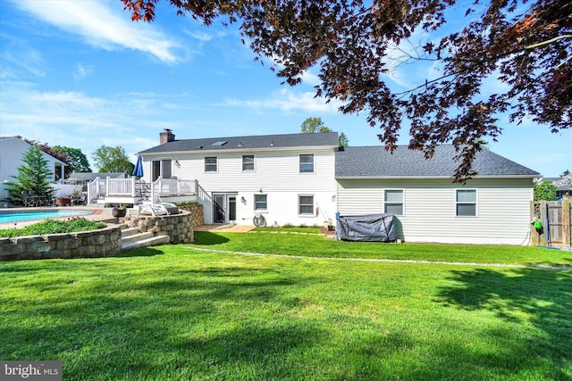 rear view of house with a lawn, fence, a wooden deck, and stairway