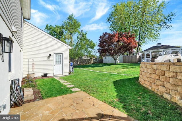 view of yard featuring a fenced backyard, a storage unit, an outdoor structure, and a patio