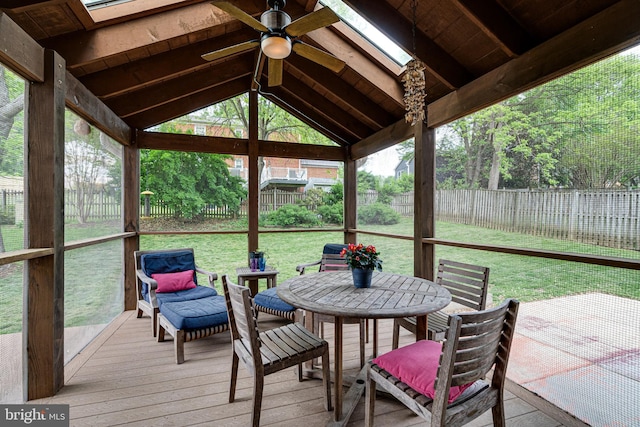 sunroom featuring a skylight, a ceiling fan, outdoor dining space, and beam ceiling