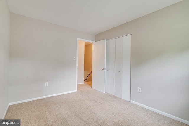 unfurnished bedroom with carpet floors, baseboards, and a closet