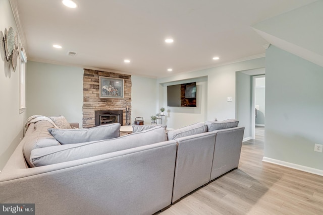 living area with light wood-style floors, a stone fireplace, recessed lighting, visible vents, and ornamental molding