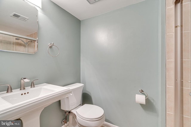 bathroom featuring walk in shower, toilet, visible vents, and a sink