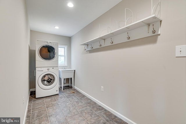 laundry area featuring laundry area, a sink, recessed lighting, baseboards, and stacked washer / dryer