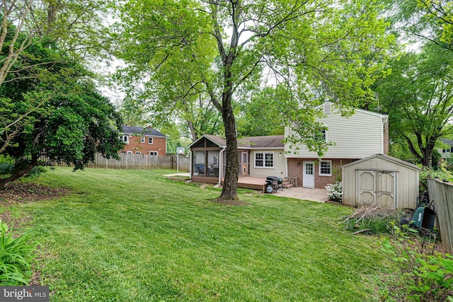 view of yard featuring an outdoor structure, fence, a wooden deck, a sunroom, and a storage shed