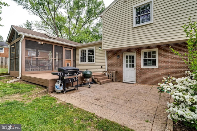 back of property featuring a sunroom, a patio area, and brick siding