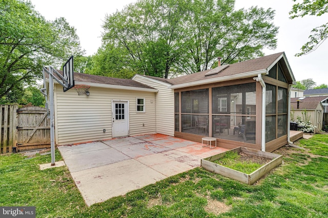 rear view of house featuring a sunroom, a lawn, a gate, and a patio area