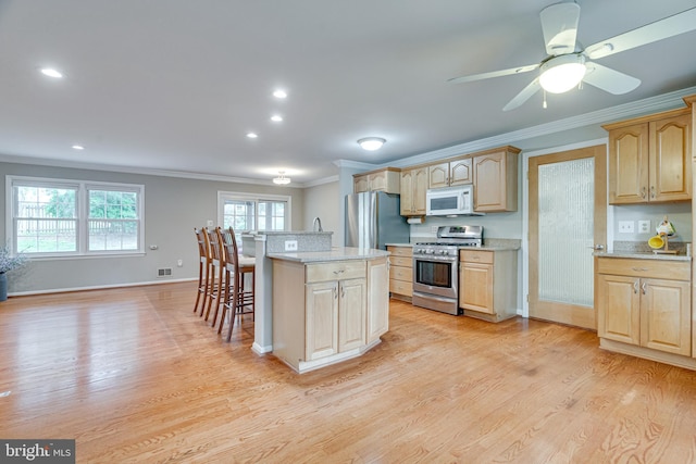 kitchen featuring crown molding, stainless steel appliances, a breakfast bar, and light wood finished floors