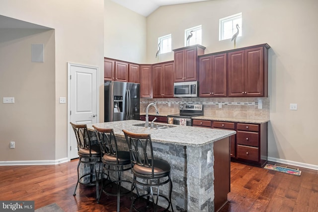 kitchen featuring a sink, appliances with stainless steel finishes, dark wood-style floors, baseboards, and high vaulted ceiling