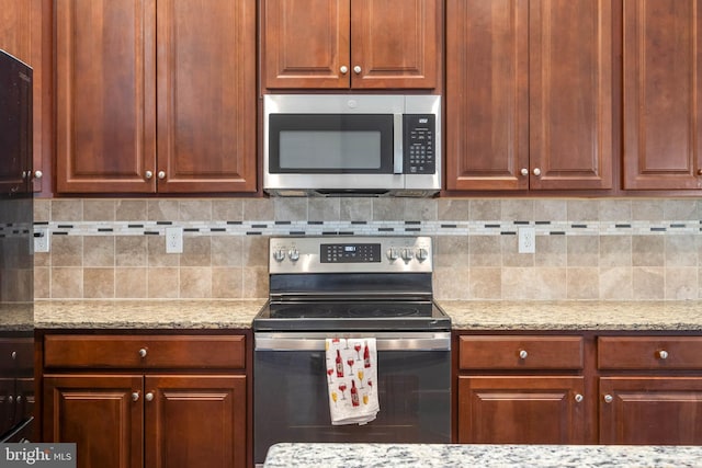 kitchen with backsplash, appliances with stainless steel finishes, and light stone counters