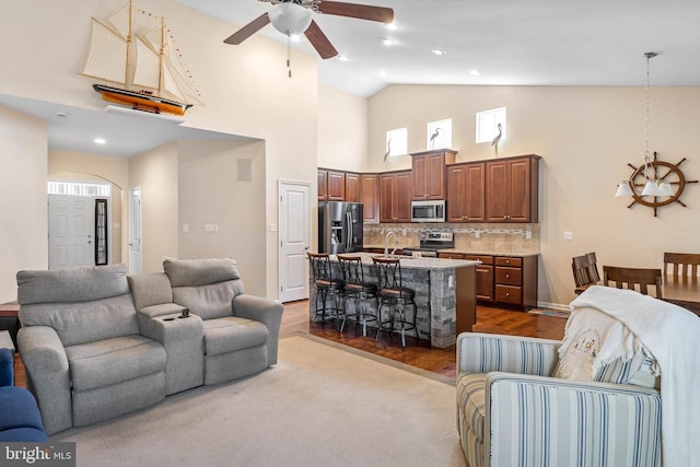 living room with ceiling fan, high vaulted ceiling, dark wood-style floors, and arched walkways