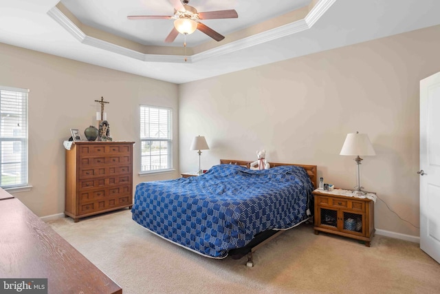 carpeted bedroom featuring crown molding, a tray ceiling, a ceiling fan, and baseboards