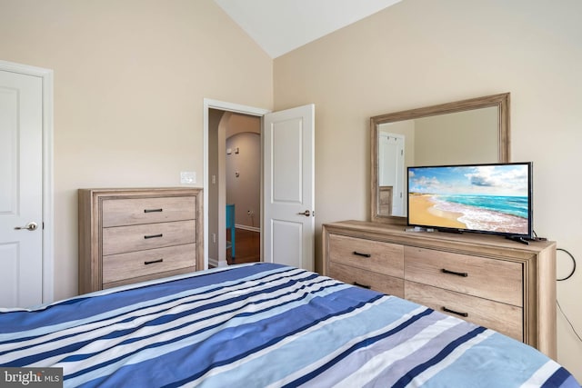 bedroom with arched walkways and vaulted ceiling