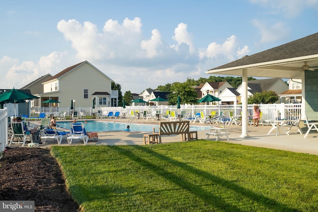 pool featuring a lawn, a patio area, and fence