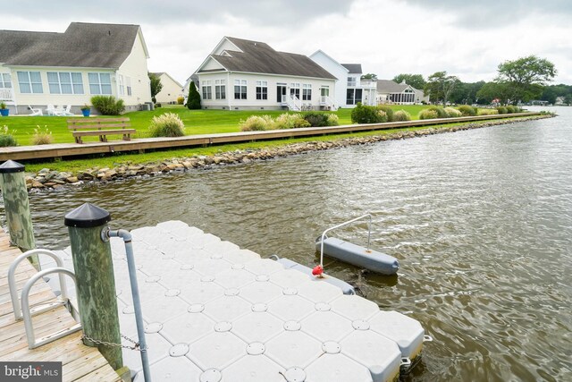 view of dock with a yard and a water view