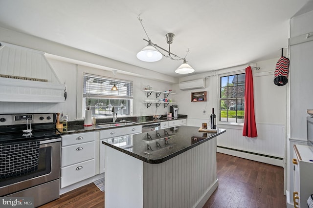 kitchen with appliances with stainless steel finishes, a sink, baseboard heating, a wall unit AC, and dark wood-type flooring