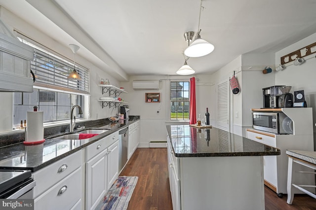 kitchen with a center island, a wall mounted air conditioner, a sink, white cabinets, and stainless steel appliances