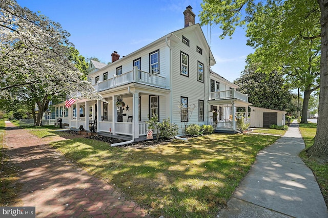 view of front facade featuring covered porch, a chimney, and a balcony