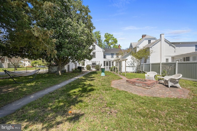 view of home's community featuring a lawn, a fire pit, fence, and a patio area