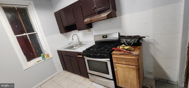 2641 N Bouvier St, Philadelphia, PA 19132 - kitchen featuring a sink, light countertops, dark brown cabinetry, under cabinet range hood, and gas stove