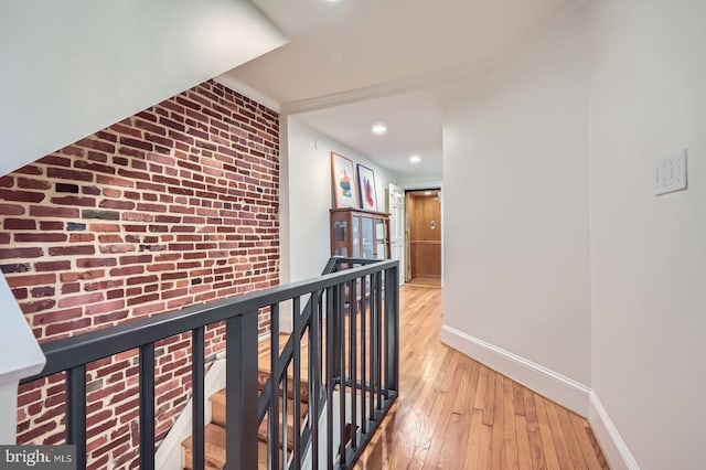 3223 Elliott St, Baltimore, MD 21224 - hallway with an upstairs landing, light wood-style floors, baseboards, brick wall, and recessed lighting