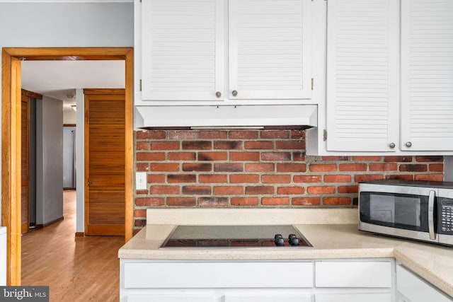 79 Darl Cir, Colonial Beach, VA 22443 - kitchen featuring stainless steel microwave, white cabinets, under cabinet range hood, black electric cooktop, and wood finished floors