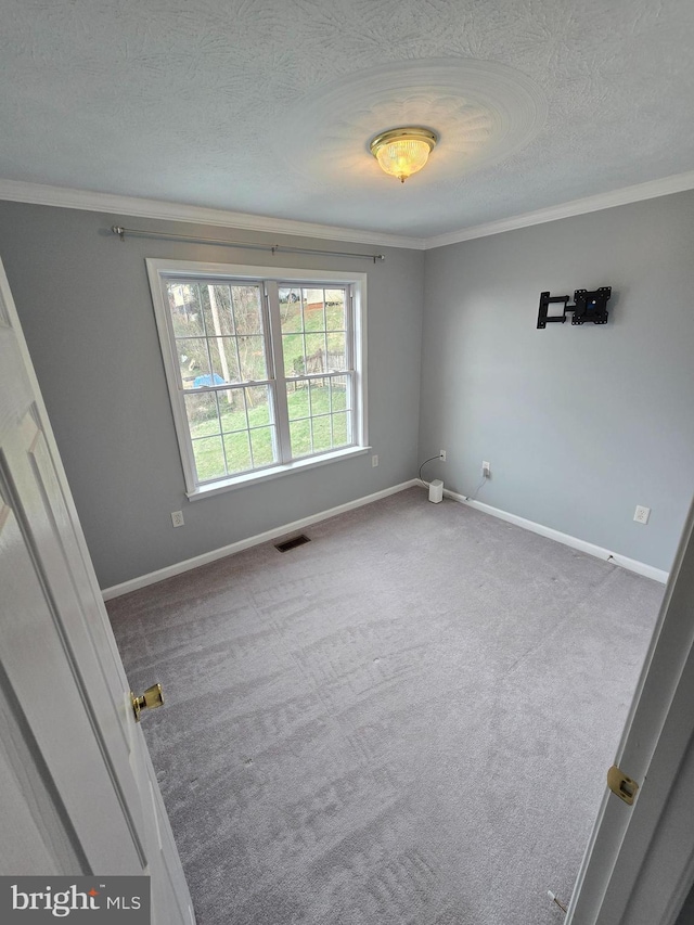 unfurnished room with baseboards, visible vents, ornamental molding, and a textured ceiling