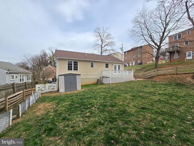 back of property with a deck, a shed, an outbuilding, a lawn, and a fenced backyard