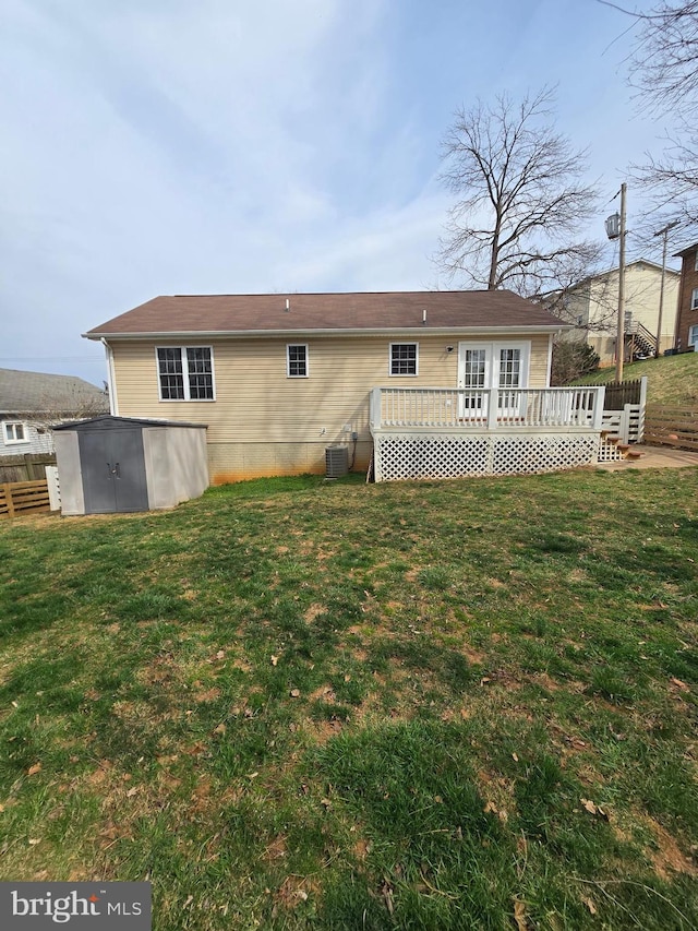 rear view of property featuring a lawn, fence, a wooden deck, and central air condition unit