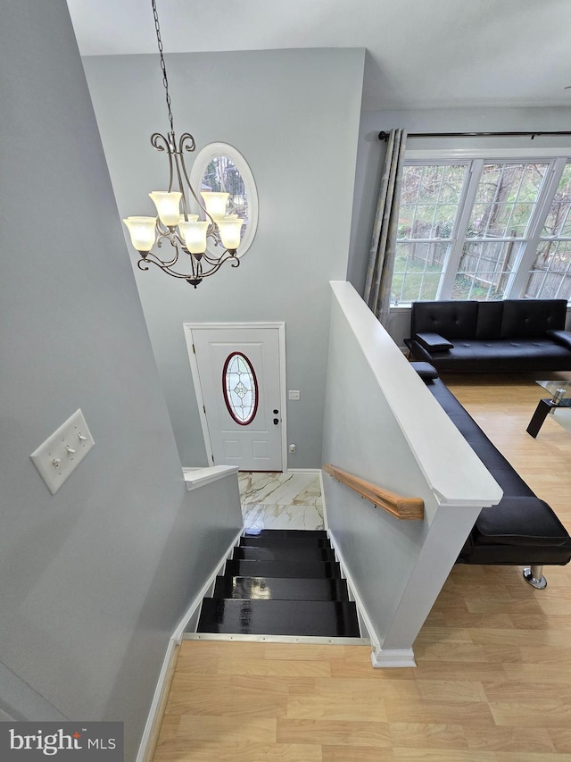 stairway featuring wood finished floors, a chandelier, and baseboards
