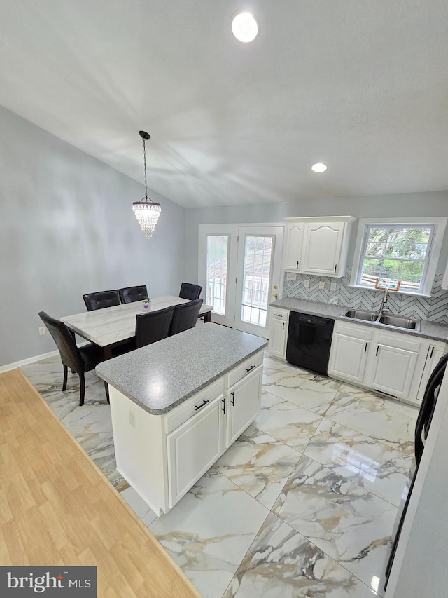 kitchen with hanging light fixtures, black dishwasher, a kitchen island, a sink, and white cabinetry