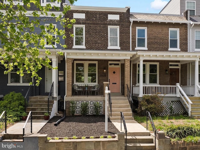 view of property with a porch, stairs, and brick siding