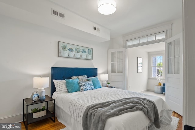 bedroom featuring baseboards, wood finished floors, and visible vents