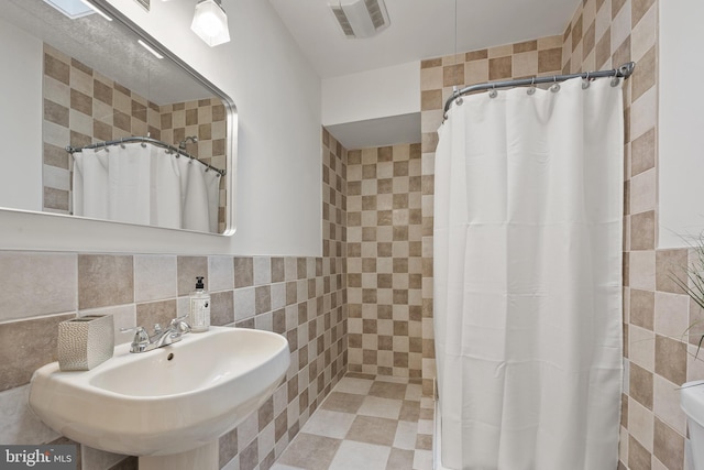 bathroom with visible vents, a sink, curtained shower, and tile walls