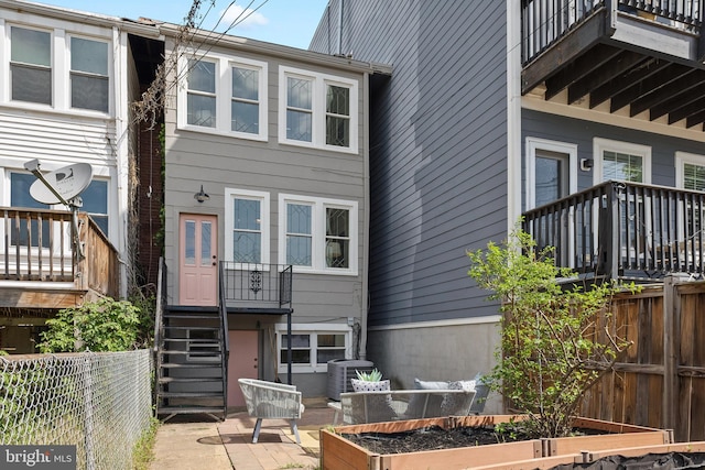 rear view of house featuring stairs, a garden, fence, and cooling unit