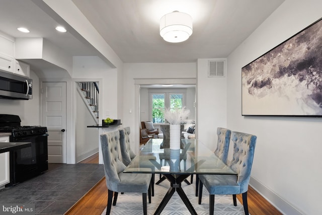 dining space with stairs, baseboards, visible vents, and dark wood-type flooring