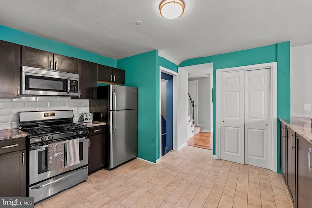6842 Queens Ferry Rd, Baltimore, MD 21239 - kitchen featuring appliances with stainless steel finishes, tasteful backsplash, light wood-style floors, dark brown cabinetry, and light stone countertops