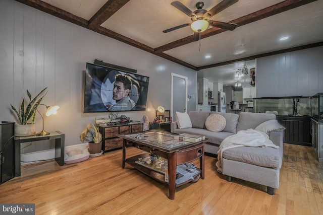 living area with a decorative wall, a ceiling fan, beamed ceiling, and light wood-type flooring