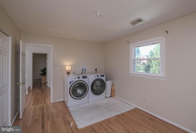 laundry room featuring separate washer and dryer, laundry area, visible vents, and light wood-style flooring
