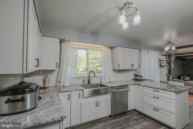 kitchen featuring white cabinets, a sink, a peninsula, decorative backsplash, and stainless steel dishwasher