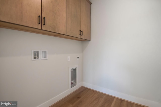 washroom with cabinet space, hookup for an electric dryer, washer hookup, baseboards, and light wood-type flooring