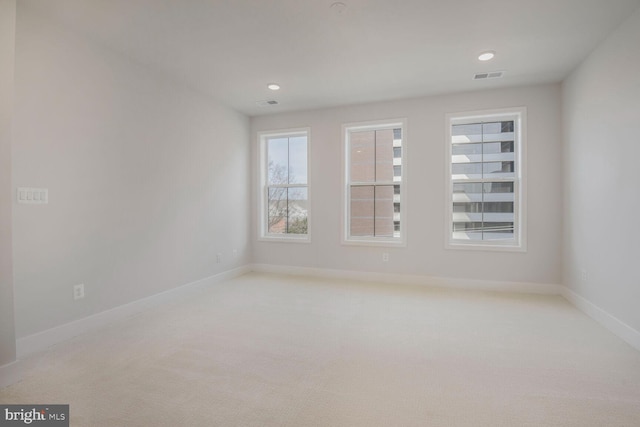empty room featuring baseboards, visible vents, light carpet, and recessed lighting