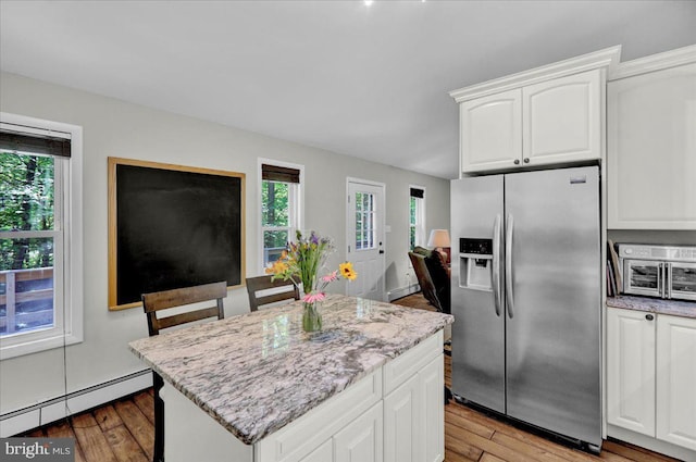 kitchen with stainless steel fridge with ice dispenser, a baseboard radiator, hardwood / wood-style flooring, and light stone counters