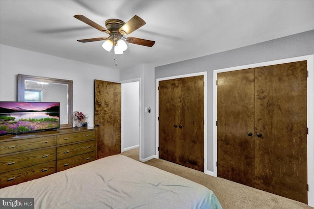 bedroom featuring carpet floors, two closets, baseboards, and a ceiling fan