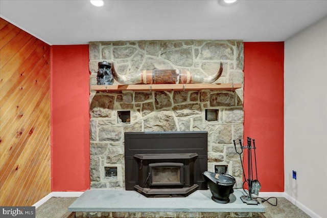 detailed view of baseboards, a wood stove, an accent wall, and wood walls