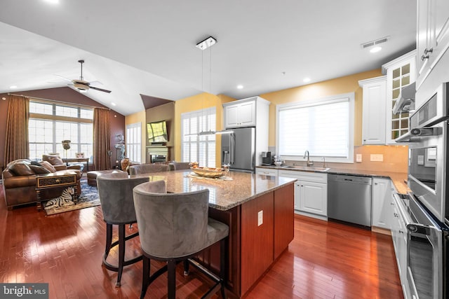 kitchen with ceiling fan, visible vents, appliances with stainless steel finishes, a sink, and open floor plan
