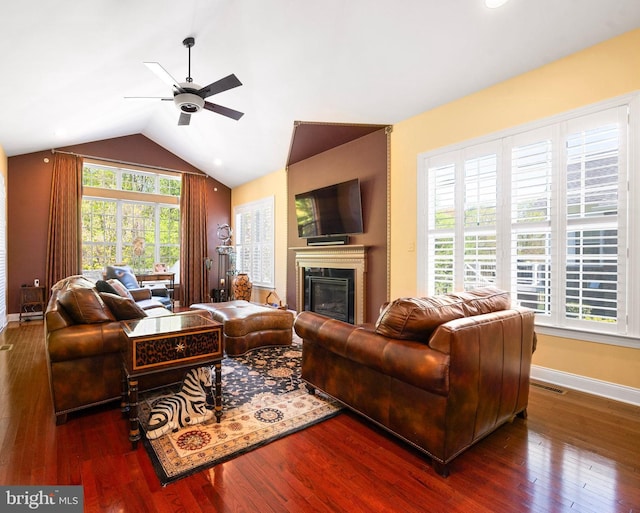 living area featuring baseboards, a glass covered fireplace, ceiling fan, and wood finished floors