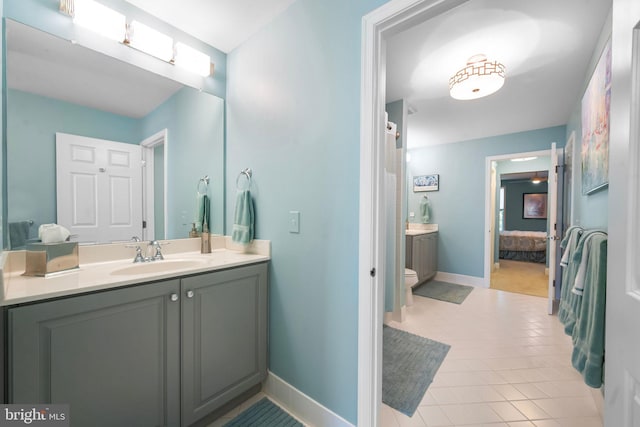 bathroom featuring baseboards, ensuite bathroom, tile patterned flooring, and vanity
